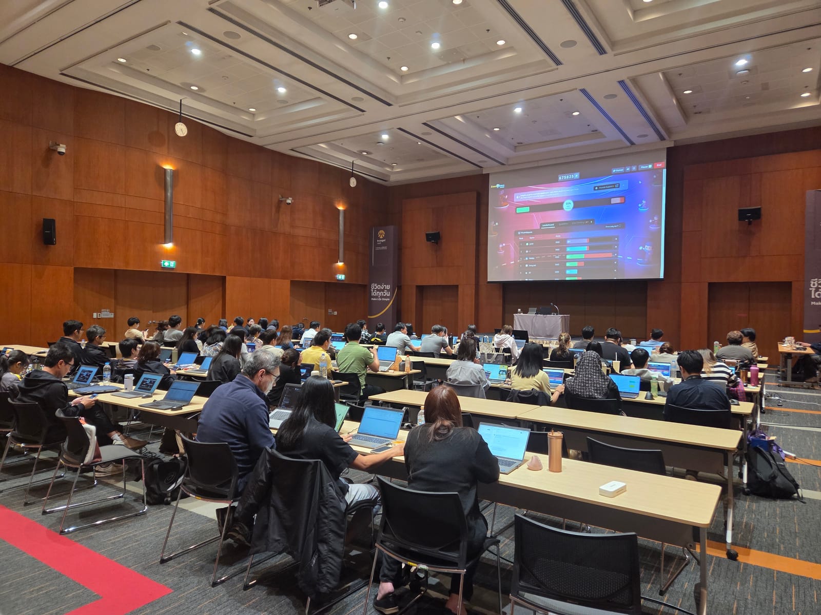 ผู้เข้าอบรมในห้องประชุมใหญ่ฝึกทำตามวิทยากร